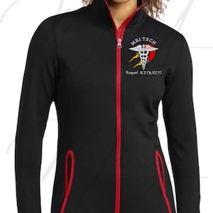 May include: A black long-sleeve zip-up jacket with red trim along the zipper and pockets. The left chest features a white caduceus symbol, a red and grey circular graphic, and the text MRI TECH and Raquel R.T.(R)(CT) in white lettering.