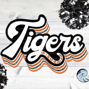 May include: A retro-style "Tigers" word art design with orange, black and silver glitter stripes. The word art is on a white wood background.