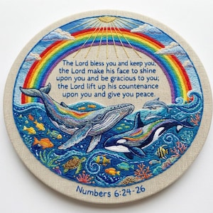 May include: A circular embroidery hoop featuring a colorful rainbow, a large whale, and an orca swimming in blue ocean waves with various fish, coral, and sea turtles. The text reads: The Lord bless you and keep you, Numbers 6:24-26.