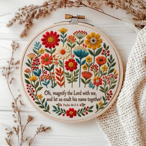 Peut inclure: Un tambour à broder circulaire contenant un tissu blanc cassé avec un motif floral coloré et le texte : Oh, magnify the Lord with me, and let us exalt his name together! Psalm 34:3-5. Les fleurs sont dans des tons de rouge, orange, jaune et bleu.