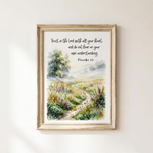 May include: A framed wall art print featuring a watercolour landscape of a winding path through a wildflower meadow with trees in the distance. The text reads: Trust in the Lord with all your heart, and do not lean on your own understanding. Proverbs 3:5.