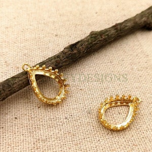 May include: Two gold-colored teardrop-shaped pendant settings with a beaded edge.