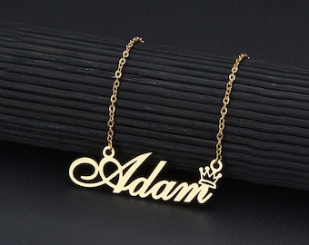 May include: Gold necklace with a cursive name pendant that says "Adam" and a small crown charm.