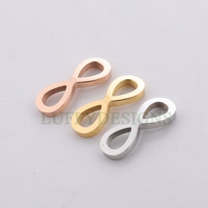 Pode incluir: Três pingentes com símbolo de infinito em diferentes acabamentos metálicos: ouro rosa, ouro e prata.