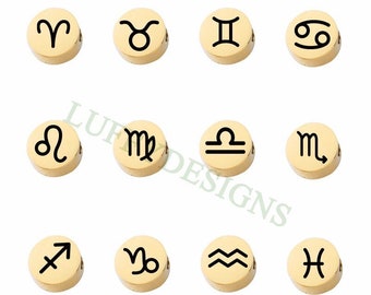 May include: Twelve gold-colored metal charms with black zodiac symbols. The symbols are Aries, Taurus, Gemini, Cancer, Leo, Virgo, Libra, Scorpio, Sagittarius, Capricorn, Aquarius, and Pisces.