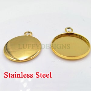 Könnte beinhalten: Zwei runde goldfarbene Metall-Anhänger-Rohlinge mit einer Öse oben. Die Anhänger-Rohlinge sind aus Edelstahl.