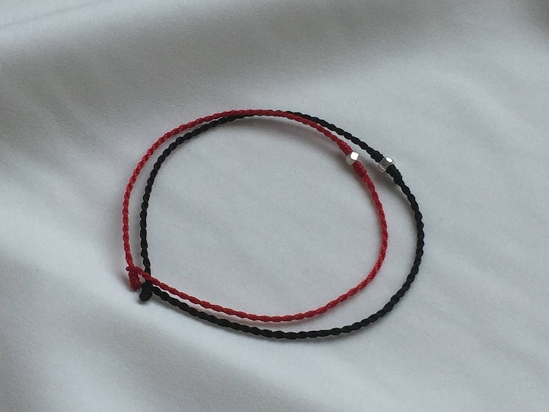 May include: A red and black braided bracelet with silver metal accents.