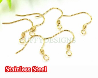 May include: Five gold-colored earring hooks made of stainless steel. The hooks are all the same size and shape, with a small loop at the top and a curved wire that ends in a point. The hooks are arranged in a random pattern on a white background.