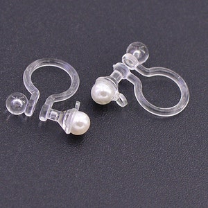 May include: A pair of clear plastic earring clips with a pearl-like bead on each clip.