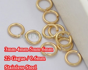 May include: A collection of gold-coloured jump rings in various sizes, including 3mm, 4mm, 5mm, and 6mm. The rings are made of stainless steel and are 0.6mm thick. The text "22 Gague / 0.6mm" and "Stainless Steel" is visible in the image.