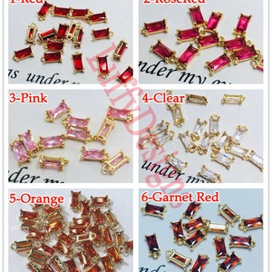 May include: Assortment of 10mm gold-tone metal connector charms with various colored crystal stones. The colors include red, rose red, pink, clear, orange, and garnet red.