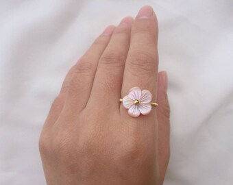 May include: A delicate gold ring featuring a pink and white shell flower design.