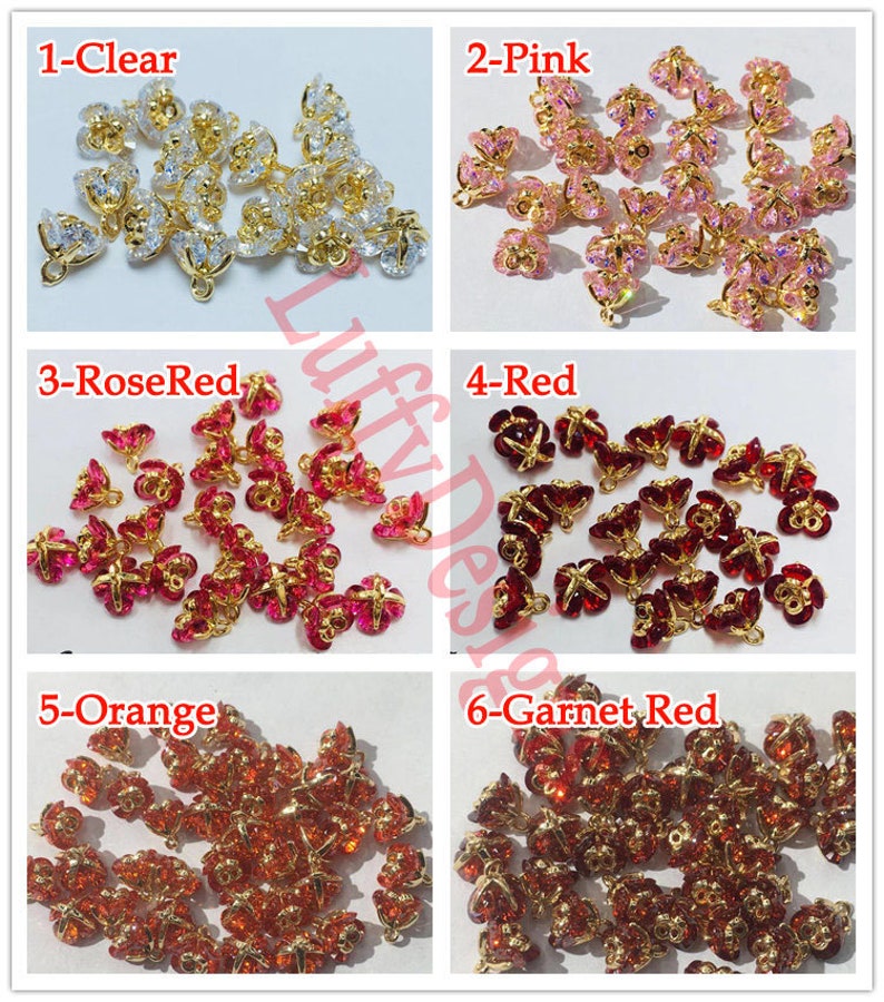 May include: Assortment of 20 gold-tone metal flower-shaped charms with crystal accents in six colors: clear, pink, rose red, red, orange, and garnet red.