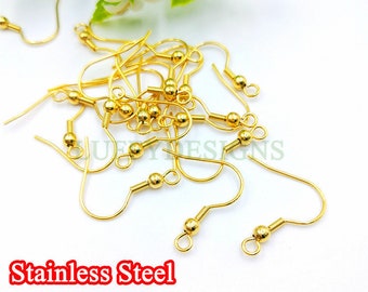 May include: A pile of gold-colored earring hooks made of stainless steel. The hooks have a small ball at the top and a loop at the bottom.