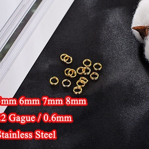 Pode incluir: Close-up de um grupo de argolas de salto douradas em vários tamanhos, 5 mm, 6 mm, 7 mm e 8 mm. As argolas são feitas de aço inoxidável de calibre 22, que tem 0,6 mm de espessura.