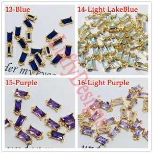 May include: Assortment of gold-toned metal connector charms with different colored glass stones. The stones are blue, light blue, purple, and light purple. The charms are rectangular with a loop at the top.