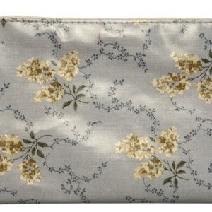 May include: A light blue zippered pouch with a floral pattern of small yellow flowers and green leaves. The pouch has a white zipper and a small white label with the text "A. HARRISON" on it.