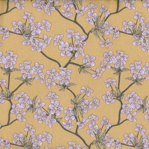 Op de afbeelding: Een stof met een herhalend bloemenpatroon. Het ontwerp toont lichtpaarse bloesems en groene bladeren op donkere stelen tegen een goudgele achtergrond. Het patroon is dicht en bedekt het gehele oppervlak.