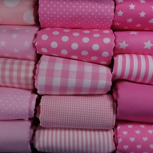 Könnte beinhalten: Ein Stapel rosa Stoffrollen mit verschiedenen Mustern, darunter Punkte, Sterne, Gingham und Streifen.