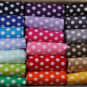 Könnte beinhalten: Eine Sammlung von 15 Stoffrollen mit weißen Punkten auf verschiedenen farbigen Hintergründen. Die Farben umfassen Marineblau, Lila, Helllila, Grau, Hellgrau, Olivgrün, Beige, Orange, Rot, Rosa, Hellblau, Türkis, Grün und Limettengrün.