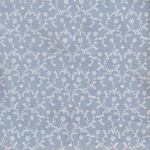 Könnte beinhalten: Ein hellblauer Stoff mit einem weißen Blumenmuster. Das Muster zeigt kleine weiße Blüten und Blätter, die in einem sich wiederholenden Design angeordnet sind. Der Stoff hat eine subtile Textur.