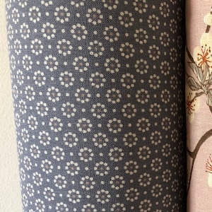 Könnte beinhalten: Nahaufnahme eines Stoffes mit einem sich wiederholenden Muster aus kleinen weißen Kreisen auf dunkelblauem Hintergrund.