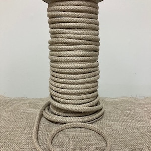 Op de afbeelding: Een spoel met natuurlijke beige katoenen touw, strak opgerold en klaar voor gebruik bij knutselen, macramé of andere projecten.