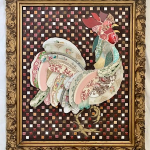 May include: A framed artwork featuring a rooster collage. The rooster is constructed from patterned china plates and fabric, set against a mosaic background. The frame is ornate gold. The rooster's colors include red, pink, green, and white.