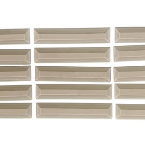 May include: A collection of rectangular, light beige ceramic tiles. Each tile has a beveled edge, creating a subtle, framed appearance. The tiles are arranged in a grid-like pattern, suggesting a design for a backsplash or wall covering.