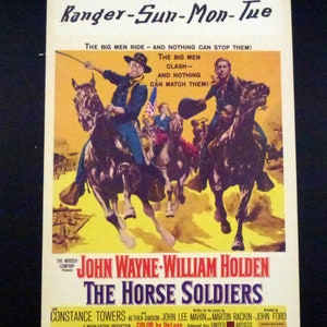 Peut inclure: Une affiche de film vintage pour le film "Les Cavaliers de l'enfer" avec John Wayne et William Holden. L'affiche présente une scène des deux acteurs à cheval, avec le titre du film en grandes lettres audacieuses.