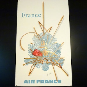 Könnte beinhalten: Ein Vintage-Reiseposter von Air France mit einem stilisierten Grafikdesign mit einem roten Herzen und goldenen Linien auf weißem Hintergrund. Der Text "France" und "Air France" ist in Blau.