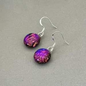 May include: A pair of silver dangle earrings with iridescent purple and pink glass round beads.