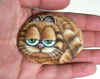 The Garfield Cartoon Cat Hand Painted Pebble! Painted with Acrylic paints and finished with satin varnish. Cat stone art, pebble painting.