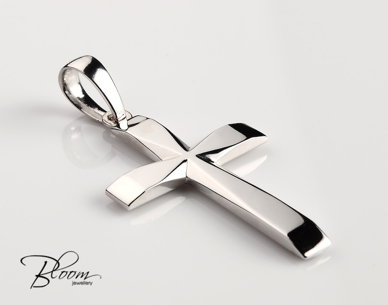 K&ouml;nnte beinhalten: Ein silberner Kreuzanh&auml;nger mit einem schlichten, eleganten Design. Das Kreuz ist aus poliertem Metall gefertigt und hat eine glatte, gl&auml;nzende Oberfl&auml;che.