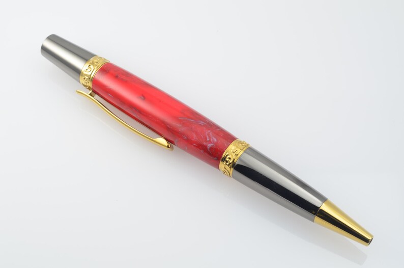 May include: A red and black pen with gold accents. The pen has a marbled red and white barrel and a black metal tip with a gold band.