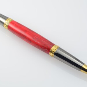 May include: A red and black pen with gold accents. The pen has a marbled red body and a black metal tip with a gold band.