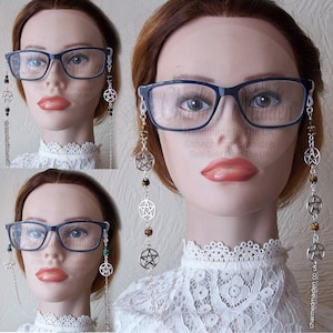 May include: A silver chain with silver pentagram charms and brown tiger eye beads. The chain is attached to a pair of blue framed glasses. The chain is a glasses chain, also known as a reading glasses chain or eyeglass chain.