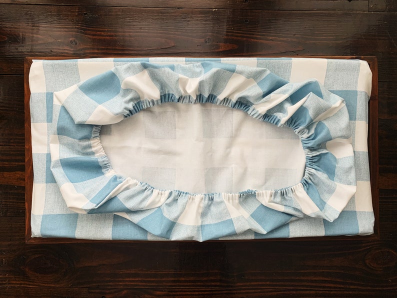 May include: A blue and white checkered fitted sheet with elastic around the edges.