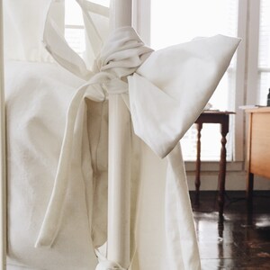 May include: White bedding with a large bow tied around a white metal bedpost.