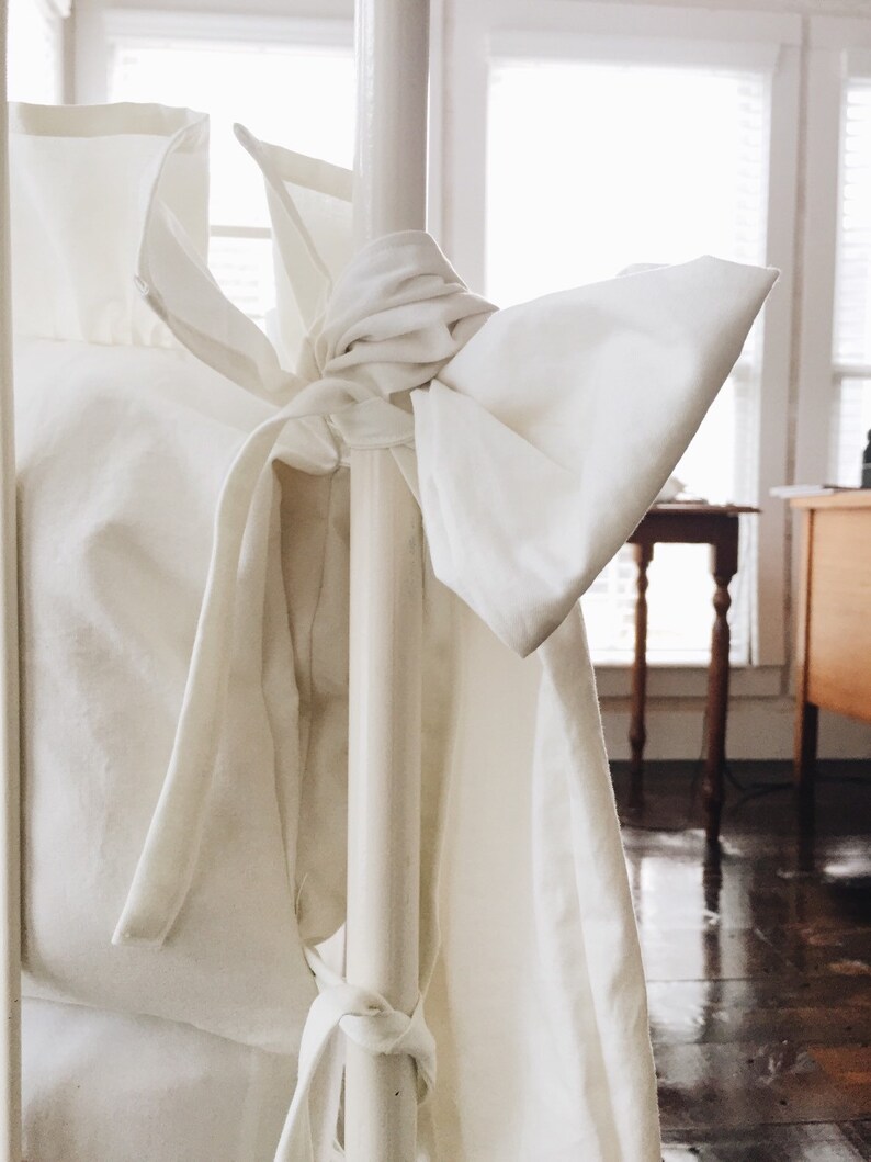 May include: White bedding with a large bow tied around a white metal bedpost.