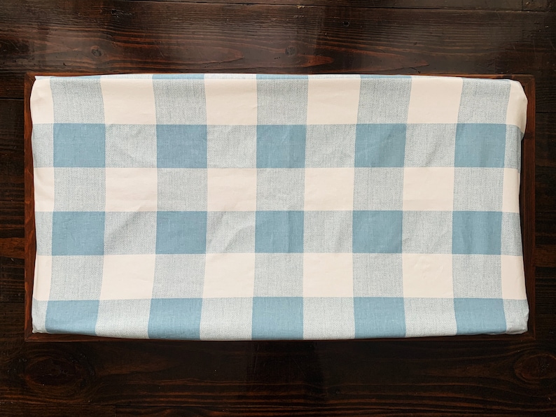May include: A blue and white gingham changing pad cover. The cover is made of a soft, comfortable fabric and is perfect for protecting your changing pad from spills and messes.