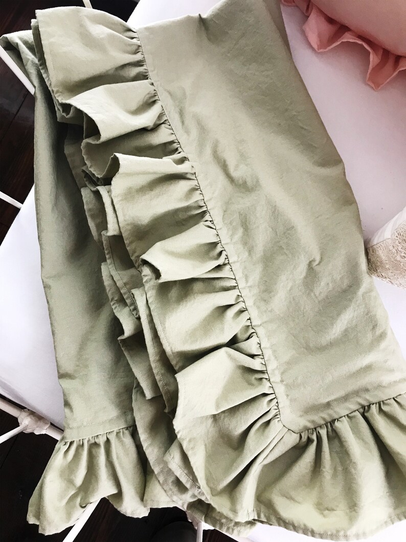 Puede incluir: Una falda de cama de color verde salvia con un borde de volantes. La falda est&aacute; hecha de una tela suave y ligera, perfecta para a&ntilde;adir un toque de elegancia a cualquier dormitorio.