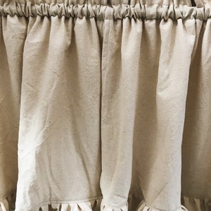 May include: A pair of off-white, ruffled curtains with a gathered top. The curtains are made of a lightweight, textured fabric.