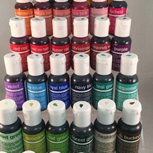 May include: A set of 30 small bottles of food coloring in various colors, including red, blue, green, purple, and yellow. The bottles are arranged in rows on a white surface.