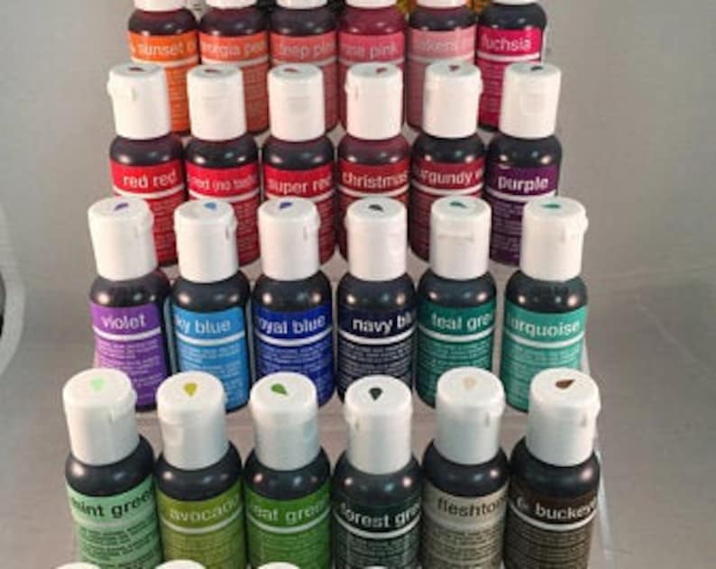 May include: A set of 30 small bottles of food coloring in various colors, including red, blue, green, purple, and yellow. The bottles are arranged in rows on a white surface.