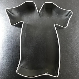 May include: A silver metal cookie cutter shaped like a t-shirt.