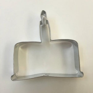 May include: A silver metal cookie cutter shaped like a birthday cake with a single candle on top.