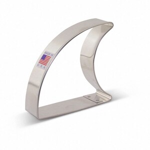 May include: A silver metal cookie cutter shaped like a shark fin. The cutter has a small American flag sticker with the text "Made in U.S.A."