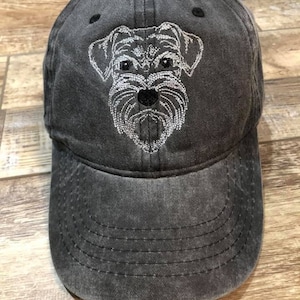 May include: A black distressed baseball cap with a white embroidered image of a schnauzer dog.