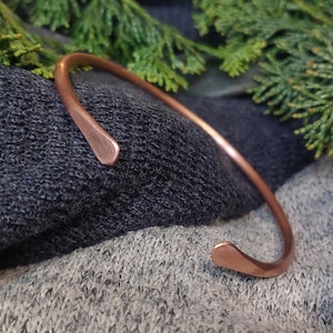 Peut inclure: Un bracelet en cuivre simple avec des extrémités arrondies. Le bracelet est de conception minimaliste et est fait d'une seule pièce de cuivre.